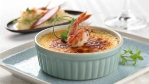 Crab Brûlée Served In An Elegant Light Blue Ramekin, Its Surface Perfectly Caramelized To A Deep Golden Brown Crust.